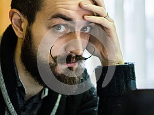 Modern, Expressive Bearded Office Clerk with Mustages Working with Notebook at Office