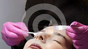 Modern eyelash healing lamination procedure in a professional beauty salon. The master applies a special cleansing foam