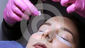 Modern eyelash lamination procedure in a professional beauty salon. The master sticks special adhesive patches on the