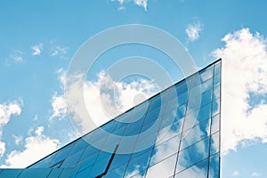 modern facade of glass and steel with reflections. Abstract or graphic photo of the sky with clouds seeming to continue into a