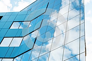 modern facade of glass and steel with reflections. Abstract or graphic photo of the sky with clouds seeming to continue