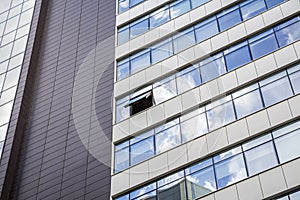 Modern facade of office building with glass and steel. One open window. Reflection sky and clouds. Exterior of futuristic business