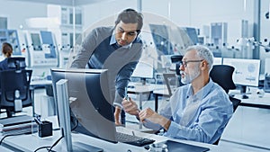 Modern Factory Office: Indian Project Manager Talks to Caucasian Senior Engineer whos Working on C photo