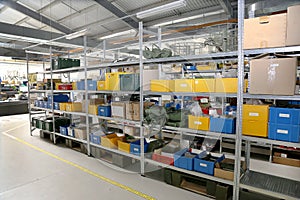 Modern factory warehouse on mechanical modern plant, colorful plastic packaging boxes, personal protection on metal racks