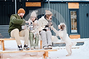 Modern Family With Dog Relaxing Outdoors On Winter Day