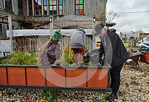 A modern family parents and children, is working together to beautify their front yard with flowers in preparation for