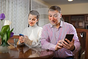 Modern family sitting with smartphones in home interior