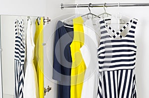 Modern fashion women's dresses on hangers in a white cupboard