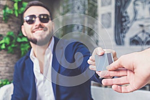 Modern fashionable man passing his credit card to waiter in cafe.