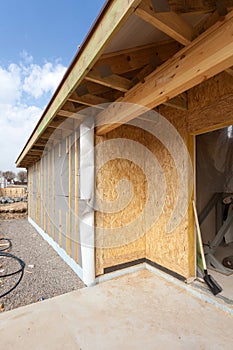 Modern frame energy efficient house under construction with membrane coverings, roof shingles and insulation materials.