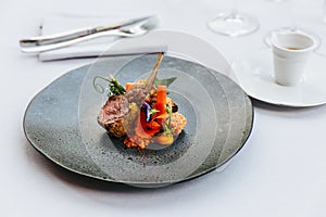 Modern French cuisine: Roasted Lamb neck & rack served with carrot, yellow curry served in black stone plate