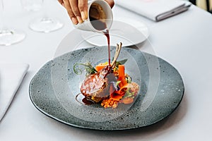 Modern French cuisine: Roasted Lamb neck & rack served with carrot, yellow curry and lamb sauce. Served in black stone plate.