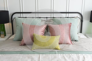 Bedroom with pastel pink and green accents pillows.