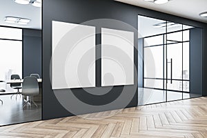 Modern gallery interior with empty white mock up frames on black wall , windows with city view, reflections on wooden parquet