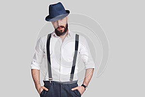 Modern gangster. Handsome young man in suspenders keeping hands