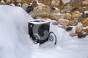 Modern garbage bin near snow bank.