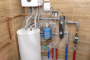 A modern gas boiler for natural gas, installed in a boiler room lined with ceramic tiles, 120 liter hot water tank visible.