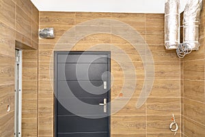 Modern gas boiler room with brown ceramic tiles imitating wood, visible air inlet and outlet, prepared for mounting the device use