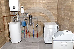 A modern gas boiler room lined with ceramic tiles imitating wood, visible full boiler room equipment with a washing machine and wa