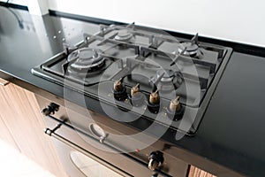 Modern gas burner and hob on a kitchen range. Dark black color and wooden Small kitchen in a modern apartment