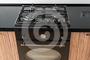 Modern gas burner and hob on a kitchen range, oven. Dark black color and wooden Small kitchen in a modern apartment