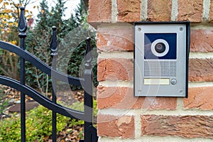 Modern gate intercom with camera on brick wall