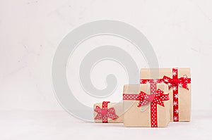 Modern gift boxes with red ribbons in elegance light white interior, copy space.