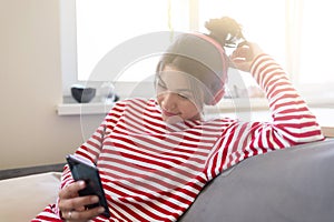 Modern  girl in wireless headphones sit relax on couch listening to music