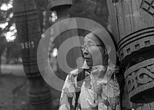 Modern girl Yakut pressed against the sacred pillar Serge in the storage of old pillars in the Park. photo