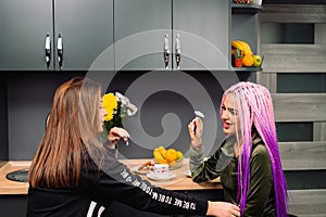 Modern girls bloggers at home in the kitchen chat and drink coffee. Girlfriends spending time.