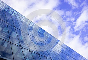 Modern glass building can accommodate offices, apartments, hotel rooms. Cloudy sky background, space.