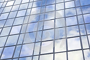 Modern glass building with reflections of blue sky and clouds