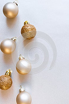 Modern glass Christmas golden minimalist balls on shiny silver background with copy space, above. New Year decor, vertical