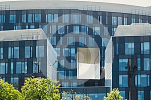 Modern glass commercial exterior of office building architecture. Window covered abstract building with green trees in