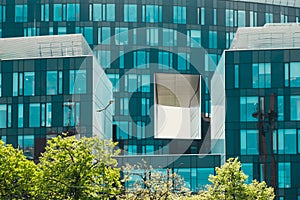 Modern glass commercial exterior of office building architecture. Window covered abstract building with green trees in