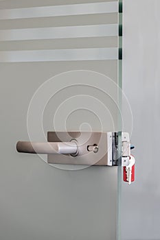 Modern glass door with metal alloy handles and key chain in lock, home or office security concept