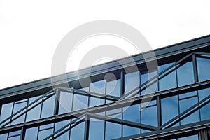 Modern glass office building exterior with glass facade on clear sky background. Transparent glass wall of office