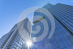 Modern glass residential buildings towering against sun and blue sky background