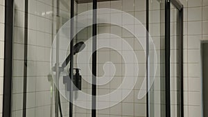 Modern glass shower in black and white bathroom close-up. Luxury hotel bathroom interior with glass shower and square