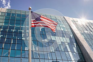 A modern glass skyscraper with an American flag flying in front under a blue sky