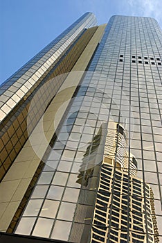 Modern glass skyscraper tall building, reflection, blue sky, vertical, front view