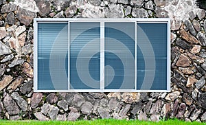 Modern glass window on the stone wall and green grass