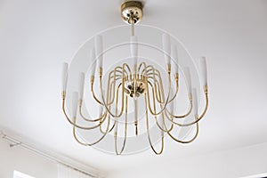 Modern gold Chandelier on a ceil in living room interior.