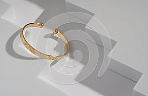Modern golden bracelet on geometric zigzag white background with copy space