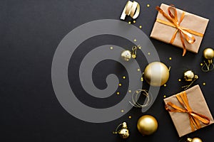 Modern golden Christmas decorations, baubles, gift boxes, confetti stars on dark black background. Flat lay design, top view, copy