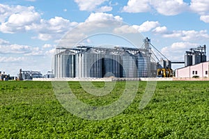 Modern Granary elevator. Silver silos on agro-processing and manufacturing plant for processing drying cleaning and storage of