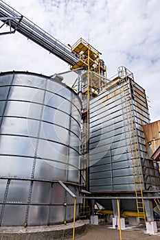 Modern Granary elevator. Silver silos on agro-processing and manufacturing plant for processing drying cleaning and storage of