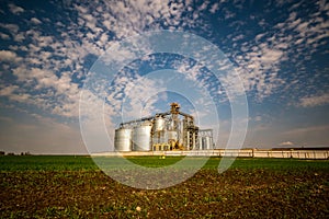 Modern Granary elevator. Silver silos on agro-processing and manufacturing plant for processing drying cleaning and storage of