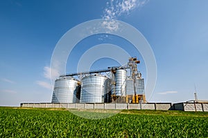 Modern Granary elevator. Silver silos on agro-processing and manufacturing plant for processing drying cleaning and storage of