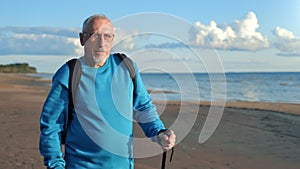 Modern grandfather elderly man Scandinavian walking stick at sunny sea beach nature landscape